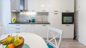 A modern kitchen with white cabinets, a black oven, and a tiled backsplash.