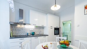 A modern kitchen with white cabinets, a tiled backsplash, and a dining area with a table set for two.