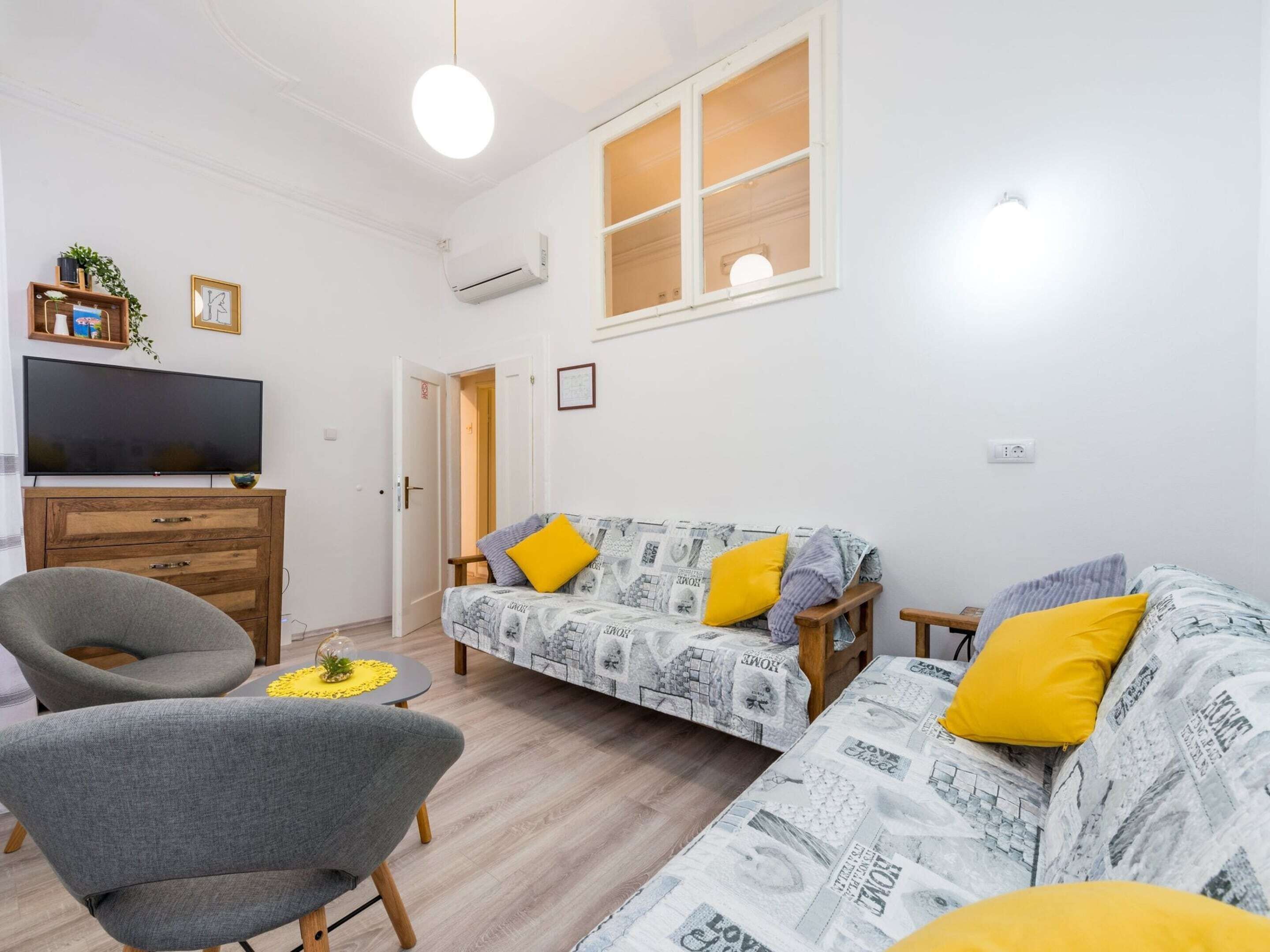 A living room with a sofa, armchair, and a television.