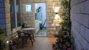 Un petit espace patio avec une table et des chaises, une plante en pot et un luminaire fixé au mur.