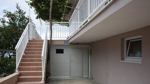 Un bâtiment doté d’un escalier menant à une porte de garage, d’une petite fenêtre et d’un balcon avec des balustrades.
