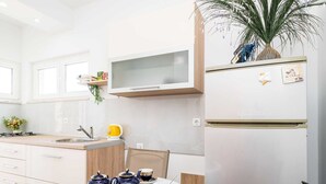 Une cuisine moderne avec des meubles blancs, un four à micro-ondes encastré et un réfrigérateur.