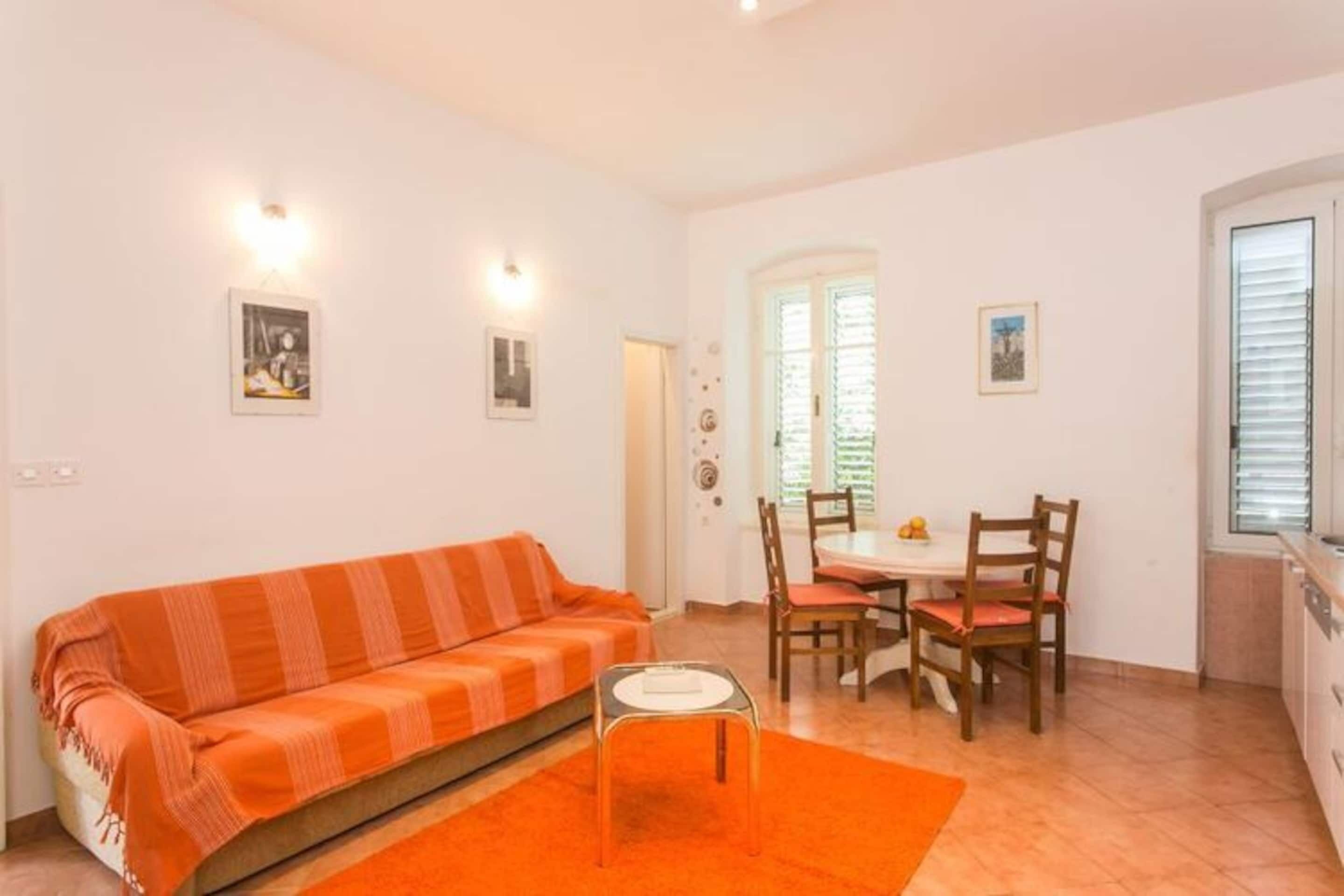 Una sala de estar con sofá, una mesa de comedor con sillas y una zona de cocina.