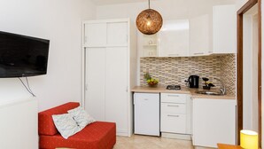 A compact kitchen with white cabinets, a built-in microwave, and a hanging light fixture. - Apartments Versus- Studio Apartment With Terrace (Zupa dubrovacka)
