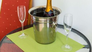 A bottle of champagne in a metal bucket with two empty glasses on a table with a green placemat. - Apartments Versus- Studio Apartment With Terrace (Zupa dubrovacka)