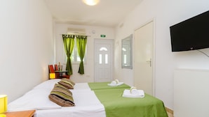 A hotel room with a bed, a desk, a chair, a television, and a door. - Apartments Versus- Studio Apartment With Terrace (Zupa dubrovacka)