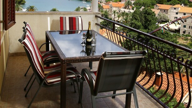 Ein Balkon mit Tisch und Stühlen, mit Blick auf einen See und eine Stadt.