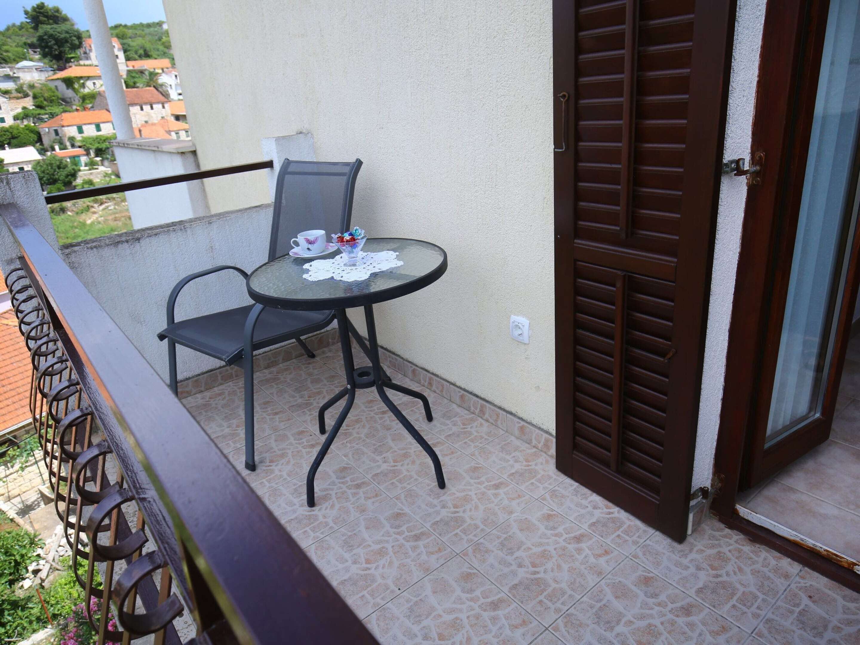 A balcony with a round table, two chairs, a cup, and a bowl of flowers.