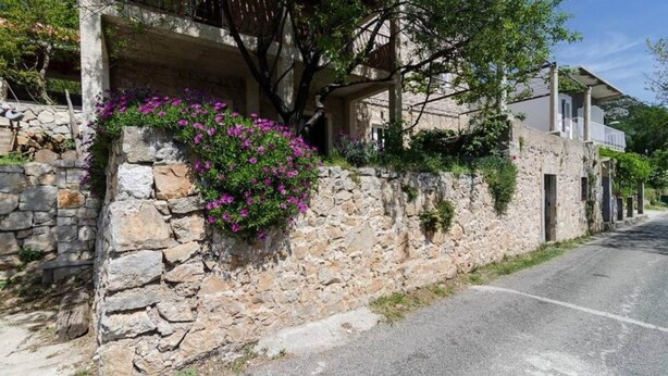 Un mur de pierre orné de plantes à fleurs et une route longeant un bâtiment.