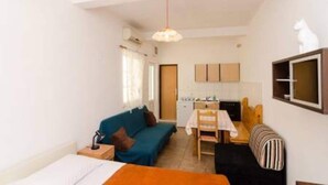 Une pièce de taille modeste comprenant un lit, un canapé, une table à manger et un coin cuisine.