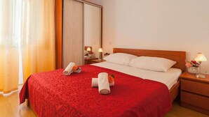 A hotel room with a large bed, a wooden headboard, a nightstand with a lamp, and a mirror.