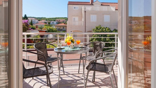 A balcony with a table and chairs, a view of buildings, and a clear sky.