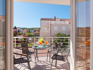 Un balcon avec une table et des chaises, une vue sur les bâtiments et un ciel dégagé.