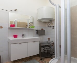 Een badkamer met een wit wastafelmeubel, spiegel en douchecel.