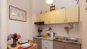 A small kitchen with a dining table set for two, a coffee maker, and a sink. - Sweetest Thing Apartment - Studio Apartment (Dubrovnik)