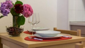 A dining table with a white plate, a glass, and a bowl of cherries. - Sweetest Thing Apartment - Studio Apartment (Dubrovnik)
