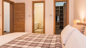 A bedroom with a bed, a wardrobe, and a bathroom visible through an open door. - Apartment in Croatia Near the Coast (Liznjan)
