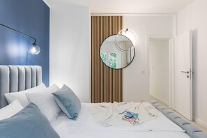 Un dormitorio moderno con cama, lámpara de noche, espejo y una puerta.