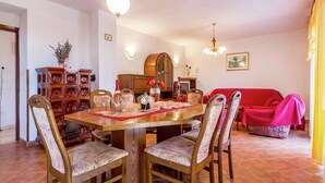 A dining room with a wooden table, chairs, and a red sofa. - Apartment in Gajana With Mini Football Field (Vodnjan)