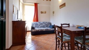 A cozy living room with a sofa, wooden dining table, and chairs. - Mansion Stay With Scenic Views (Siena)
