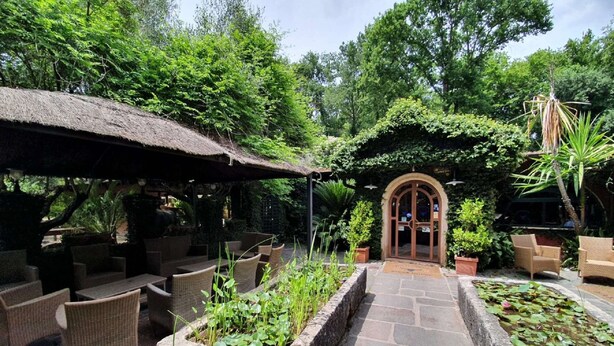 An outdoor seating area with wicker furniture and a stone pathway leading to an arched entrance.