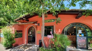 A reception area with a sign, a flamingo statue, and a window displaying a poster.
