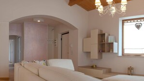 A modern living room with a sofa, a chair, and a small table. There is a window with a heart-shaped decoration.