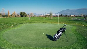 A golf course with a well-maintained green, a golf bag, and a flagstick. - Belvilla by OYO Valle di Assisi Bilo (Assisi)