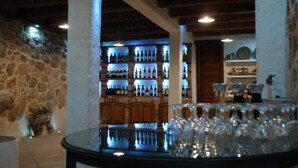 A bar area with a stone wall, wooden ceiling beams, and a bar counter with bottles and glasses. - House Rilovic - Two Bedroom House With Swimming Pool and Jacuzzi (Konavle)