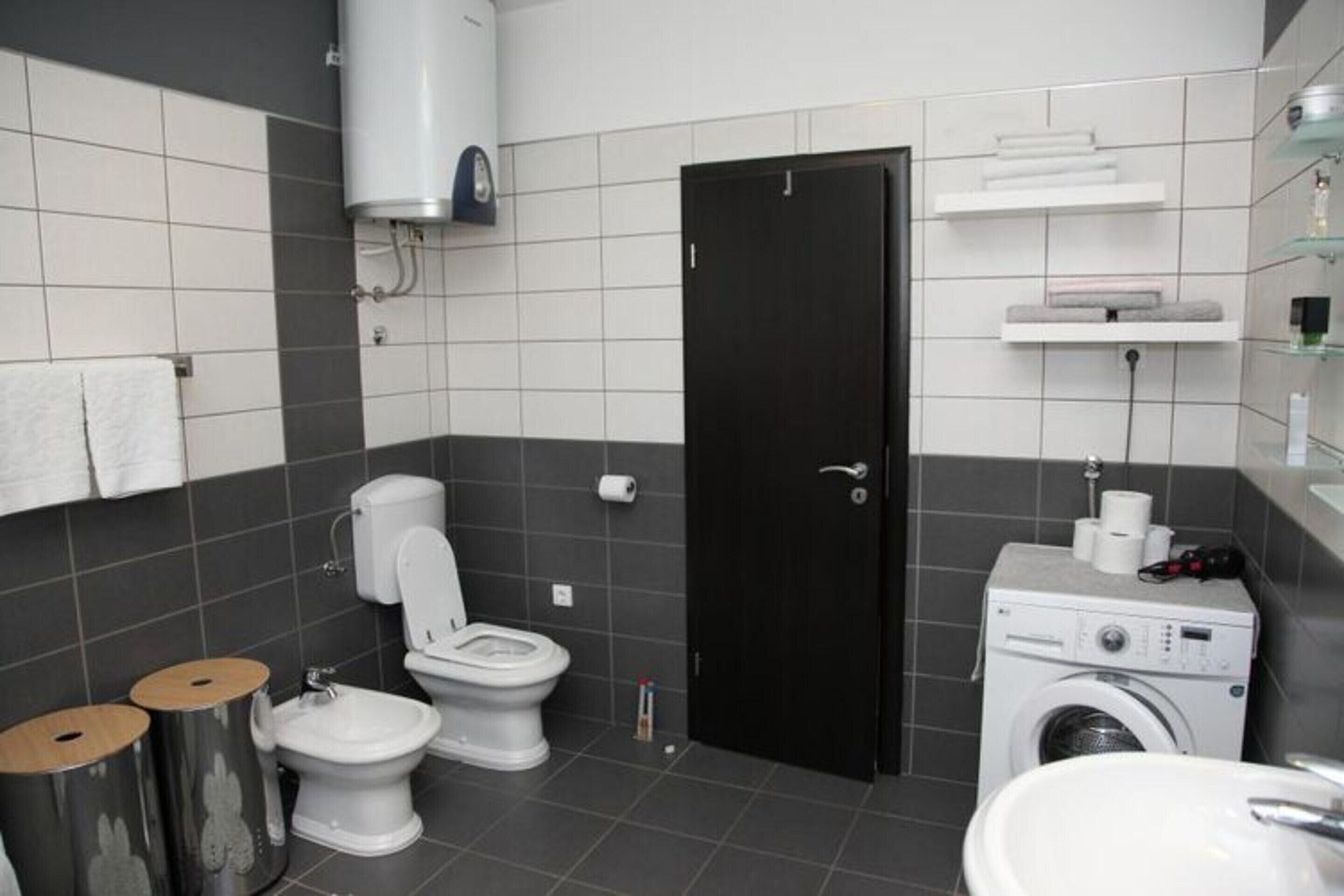 A modern bathroom with a toilet, bidet, and washing machine.