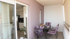 Un balcon avec une table à manger, des chaises et un canapé à rayures.