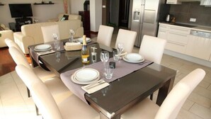 Un espace repas avec une table rectangulaire dressée pour six personnes, entourée de six chaises blanches.