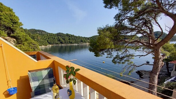 A balcony with a table set for two, overlooking a lake and forested hills. - Apartments Vinko Mljet- One-bedroom Apartment With Terrace (Mljet)