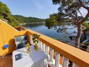 A balcony with a table set for two, overlooking a lake and forested hills. - Apartments Vinko Mljet- One-bedroom Apartment With Terrace (Mljet)