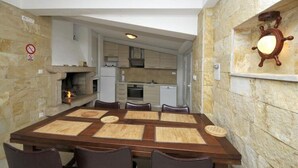 A dining area with a stone wall, a built-in oven, and a wall-mounted light fixture. - Apartments Villa Moonlight - One Bedroom Apartment With Sea View Balcony and Terrace (Okrug)