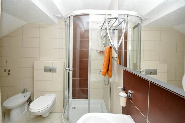 Une salle de bain moderne avec une douche à parois de verre, un lavabo blanc et des toilettes.