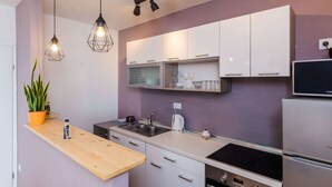 A modern kitchen with white cabinets, a wooden countertop, a built-in stove, and pendant lighting. - Apartment Konak - Two Bedroom Apartment With Balcony and Sea View (Konavle)