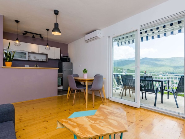 A modern kitchen with a dining area and a balcony with a scenic view.