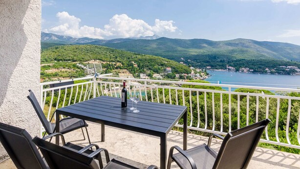 A balcony with a table and chairs, overlooking a scenic view of a lake and mountains. - Apartment Konak - Two Bedroom Apartment With Balcony and Sea View (Konavle)