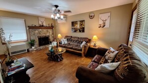 A cozy living room with a fireplace, a sofa, a coffee table, and a bookshelf.