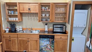 A compact kitchen with wooden cabinets, a dishwasher, a toaster, and a refrigerator.