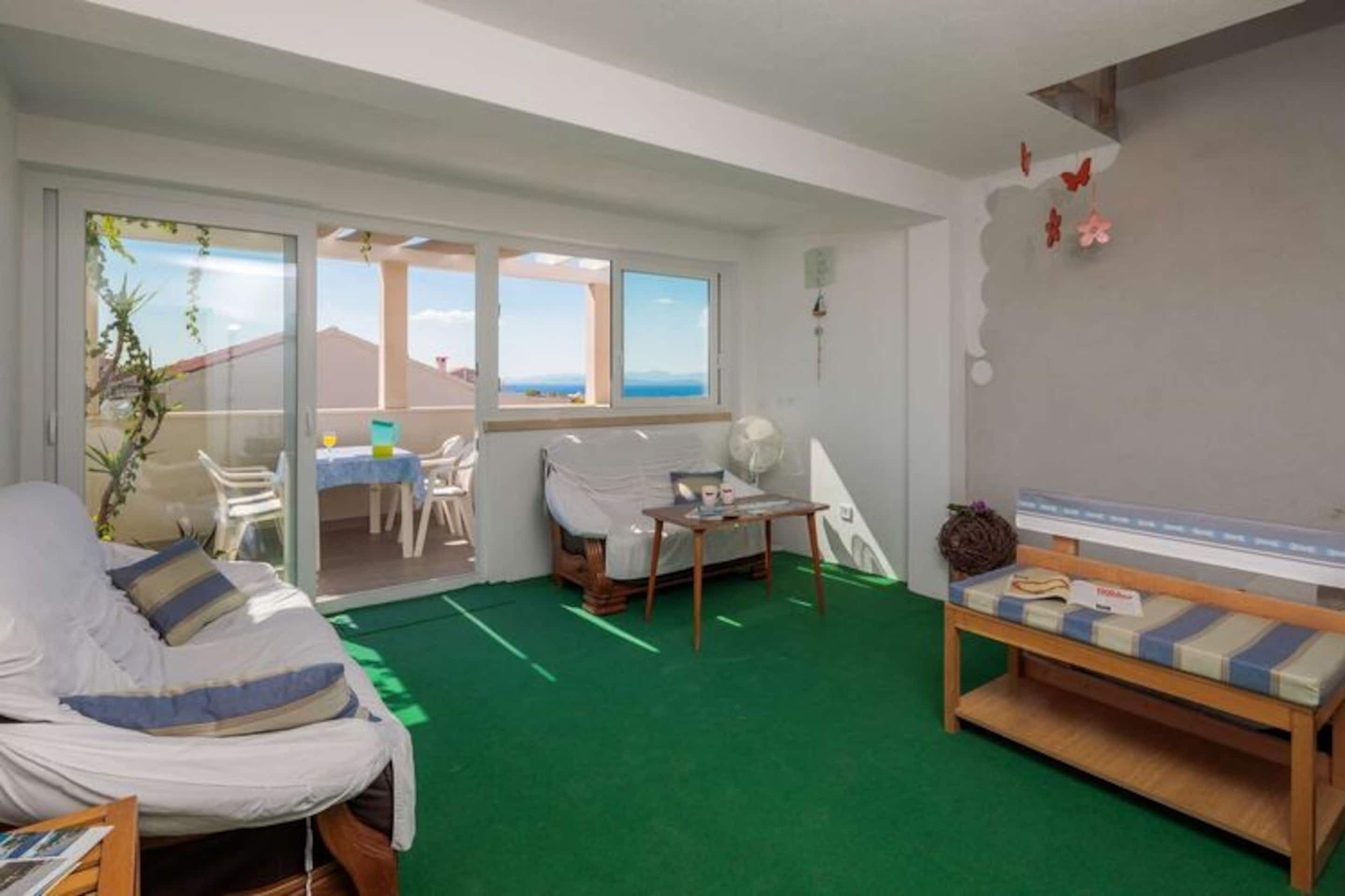 Una habitación con cama, una mesita, una silla y vistas al exterior a través de una puerta corrediza.