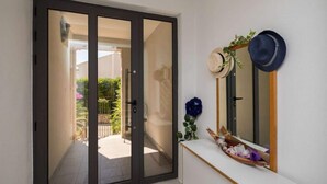 Een kamer met een schuifdeur naar een balkon, een witte console tafel met een spiegel en hoeden, en een klein beeldje.