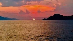 Un atardecer sobre un mar tranquilo con una masa de tierra a lo lejos.