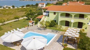 Ein zweistöckiges Gebäude mit Pool, Außenbereich und Meerblick.