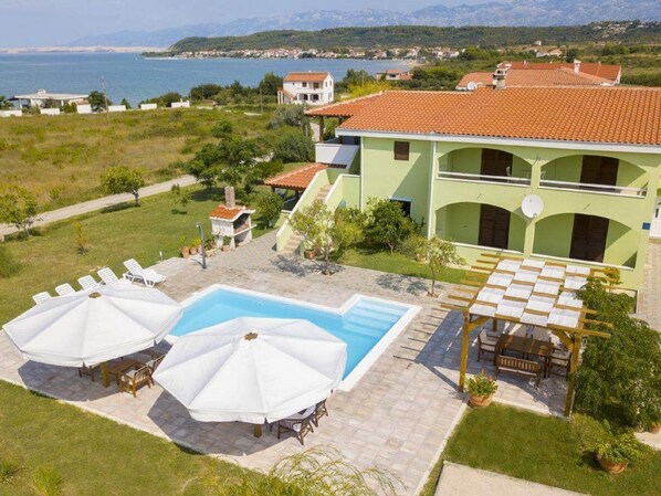 A two-story building with a swimming pool, outdoor seating, and a view of the sea. - Charming 2-bed Apartment (Razanac)