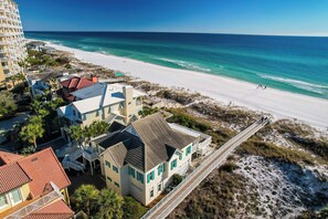 A coastal property with a beach view, a wooden boardwalk, and a mix of residential buildings.