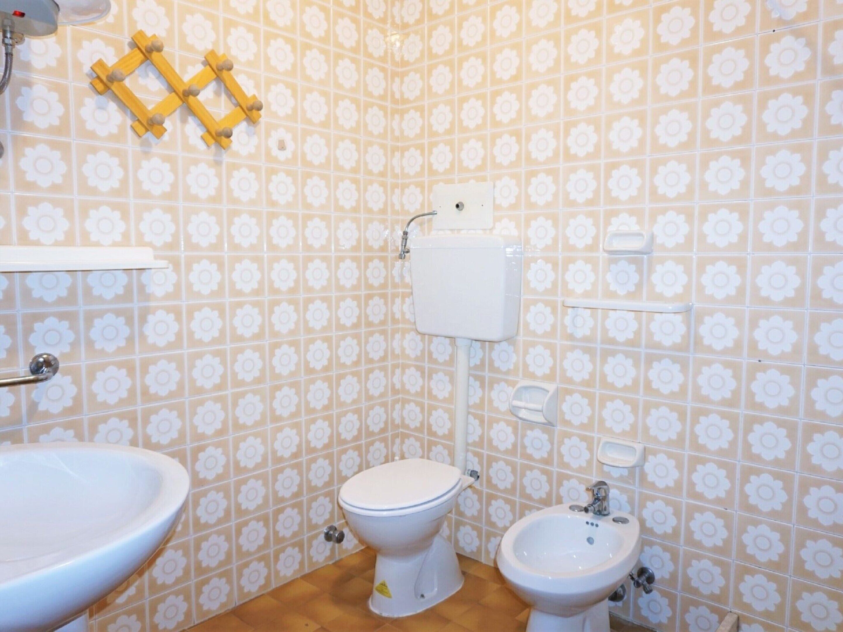 A bathroom with a toilet, bidet, and sink, all with white fixtures.