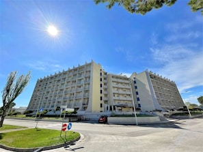 Un hotel de varios pisos con un diseño arquitectónico moderno, que cuenta con balcones y un patio central.