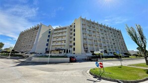 A multi-story hotel with a modern architectural design, featuring balconies and a central courtyard.
